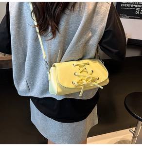 Detail of light yellow crossbody bag featuring a bow tie design and textured leather strap