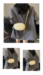 Detail view of cream-colored pebble leather crossbody bag with tassel zipper pull