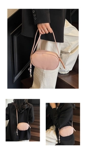 Detail view of pink pebbled leather crossbody bag with knot and metal charm accents