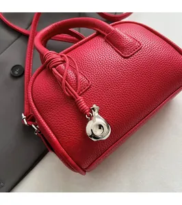 Macro shot of red pebble grain leather Boston bag with metallic pendant and handles