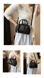 Detail of black lychee grain leather bag with knot decor and silver sphere pendant