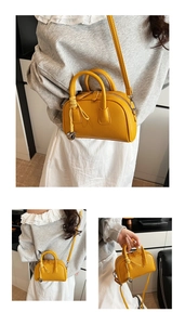 Detail of yellow pebbled leather Boston bag showing dual handles and silver bell charm