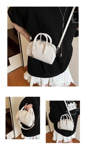 Detailed macro view of white lychee pattern leather Boston bag with silver ball pendant