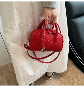 Detail of red pebbled leather Boston bag with silver zipper and decorative knot charm