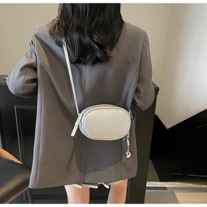 Detailed view of silver metallic textured crossbody bag with a heart-shaped metal charm