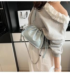 Detail of light blue glossy bucket bag with silver chain strap and ruched cloud texture