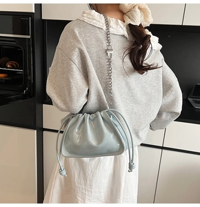 Close-up of light blue patent leather bucket bag with silver chain and pleated detail