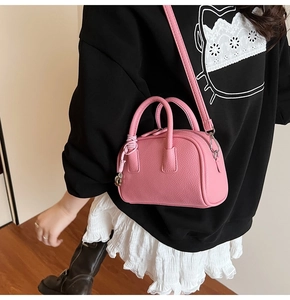 Detail of pink pebbled leather crossbody bag with knot pendant and silver hardware