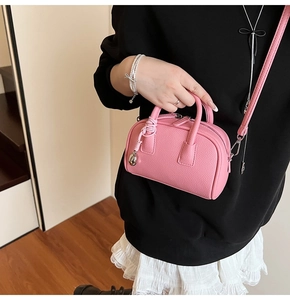 Macro detail of pink lychee grain leather handbag with round handles and metal zipper