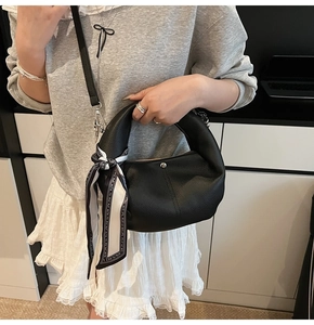 Detail of black lychee grain handbag with decorative silk scarf handle and metal buckle