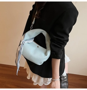 Détail d'un sac en cuir bleu clair avec foulard en soie et rivets métalliques élégants