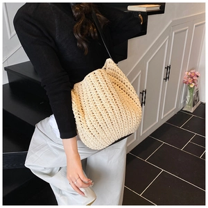 Close-up of beige crochet bucket bag featuring intricate openwork weave and black strap