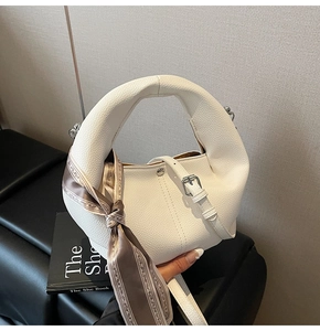 Detail der weißen Handtasche aus Litschi-Leder mit Seidenschal und Gürtelschnalle