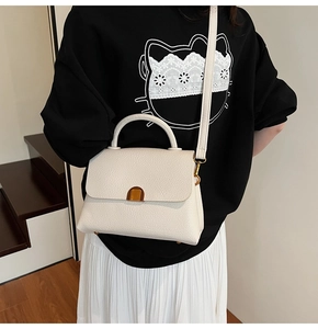 Gros plan d'un sac à main blanc en cuir grainé avec un fermoir métallique doré arrondi