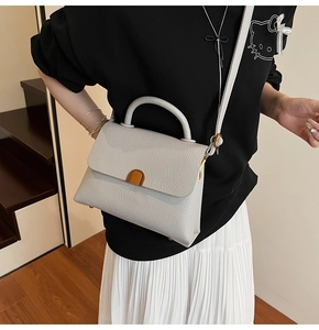 Detail of grey pebbled leather crossbody bag with gold metal lock and shoulder strap