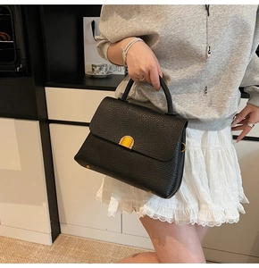 Gros plan sur la texture du cuir litchi noir avec une boucle dorée élégante