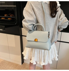 Détail du sac à main bleu clair avec texture grainée et fermoir métallique doré élégant