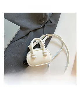 Detail view of white mini square bag with knotted base on dark grey suit jacket