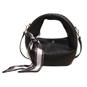 Detail of black lychee leather handbag with ring handle, silk scarf and silver clasp