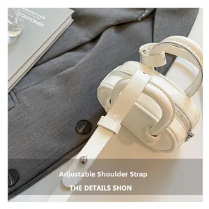 Close-up of the adjustable strap and glossy cream leather of the mini bowling bag