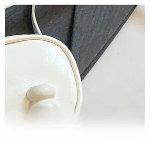 Detailed macro view of high-quality white pebbled leather texture on minimalist shoulder bag