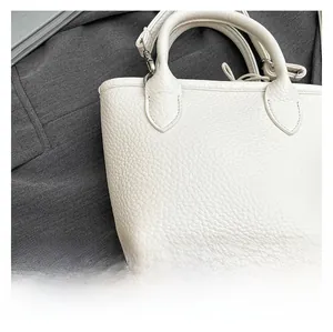 Detail of white mini tote bag with lychee texture on a dark gray blazer background