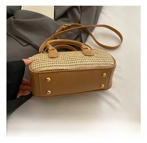 Detail view of woven straw handbag bottom with four protective gold metal feet studs
