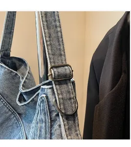 Macro shot of adjustable metal buckle and durable denim strap on a washed blue tote bag