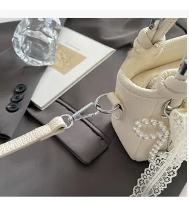 Détail d'un sac seau en cuir grainé blanc avec boucle argentée et perles chic