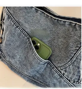 Detail of a large denim tote bag featuring a durable front pocket for a smartphone