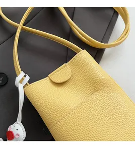 Detail of yellow lychee texture crossbody bag with cute white duck pendant charm