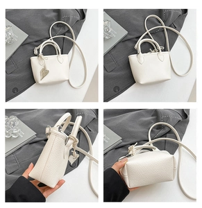 Detail view of white pebbled leather mini tote bag with silver heart charm and strap