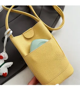 Detail of a bright yellow textured leather bucket bag with front pocket and duck pendant