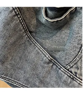 Macro shot of washed blue denim fabric texture and reinforced stitching on the tote bag