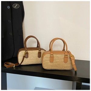 Detailed view of woven straw shoulder bags with leather trim and gold metal hardware