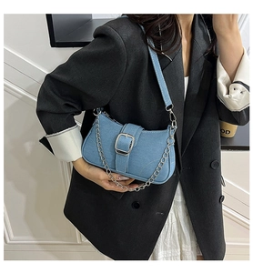 Detail of light blue denim underarm bag with silver buckle and metal chain strap