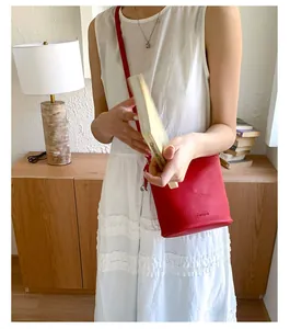 Détail du sac seau en cuir grainé rouge avec logo Pantone et fine bandoulière réglable