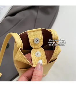 Detail of yellow lychee texture leather bag with silver magnetic snap button closure