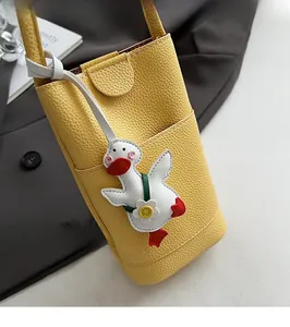 Detailed close-up of yellow pebbled leather phone bag with cute cartoon duck pendant
