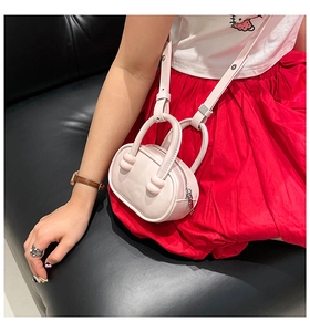 Detail view of pink mini crossbody bag with unique ball accent on top handle