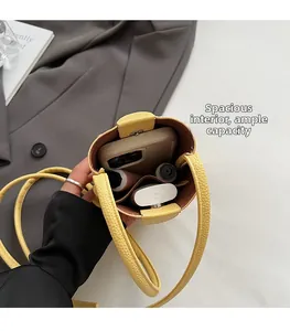 Detailed view of yellow bucket bag interior holding a phone and makeup essentials