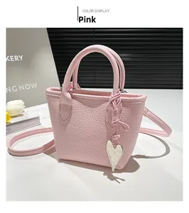 Detailed close-up of a pink litchi grain faux leather tote bag with silver heart pendant