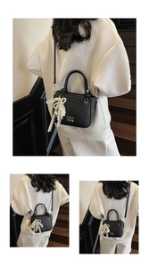 Détail du sac seau en cuir noir avec dentelle blanche et nœud en perles élégant