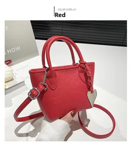 Detail of red pebbled leather mini handbag with heart-shaped silver pendant and metal hardware