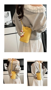 Detail of yellow pebbled leather mini crossbody bag with a cute 3D duck charm accessory