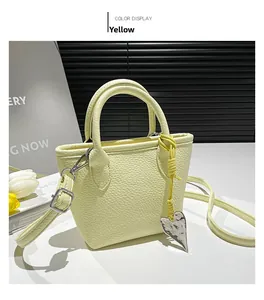 Detail of yellow lychee leather mini handbag with dual handles and silver heart charm