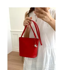 Détail du sac seau en cuir grainé rouge avec pendentif coeur argenté et bandoulière