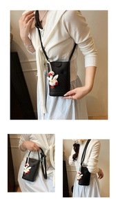 Detail view of black lychee grain phone crossbody bag with cute white duck charm accessory