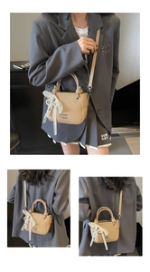 Détail d'un sac seau beige texturé avec nœud en dentelle et décoration de perles fines
