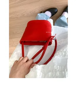 Sac seau en cuir rouge à motif litchi présenté dans une tenue de style quotidien